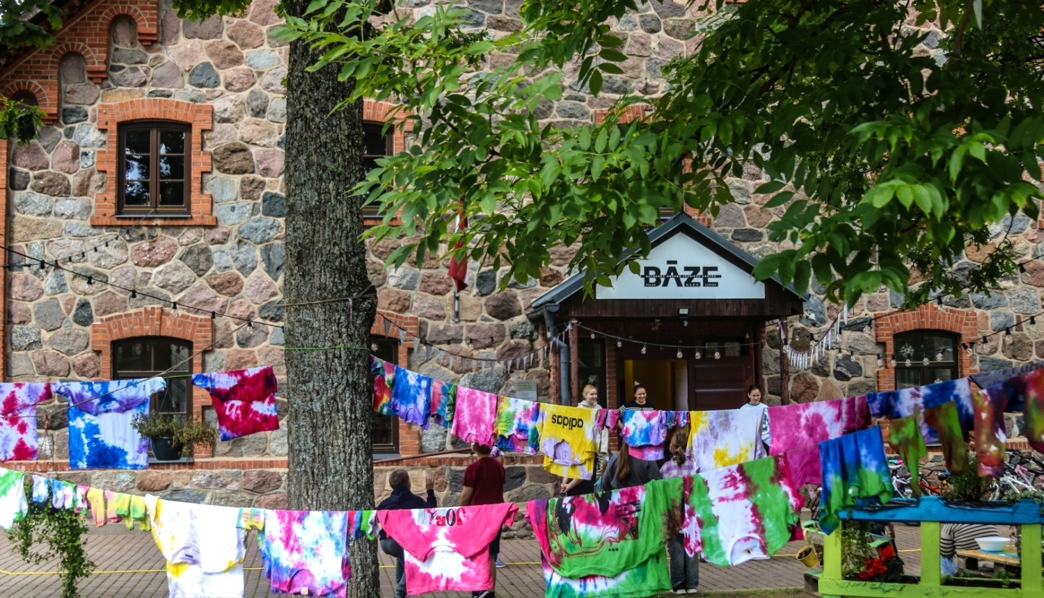 Bāzes ieeja un stilizēti krekli kā dekorācijas uz veļas auklas.